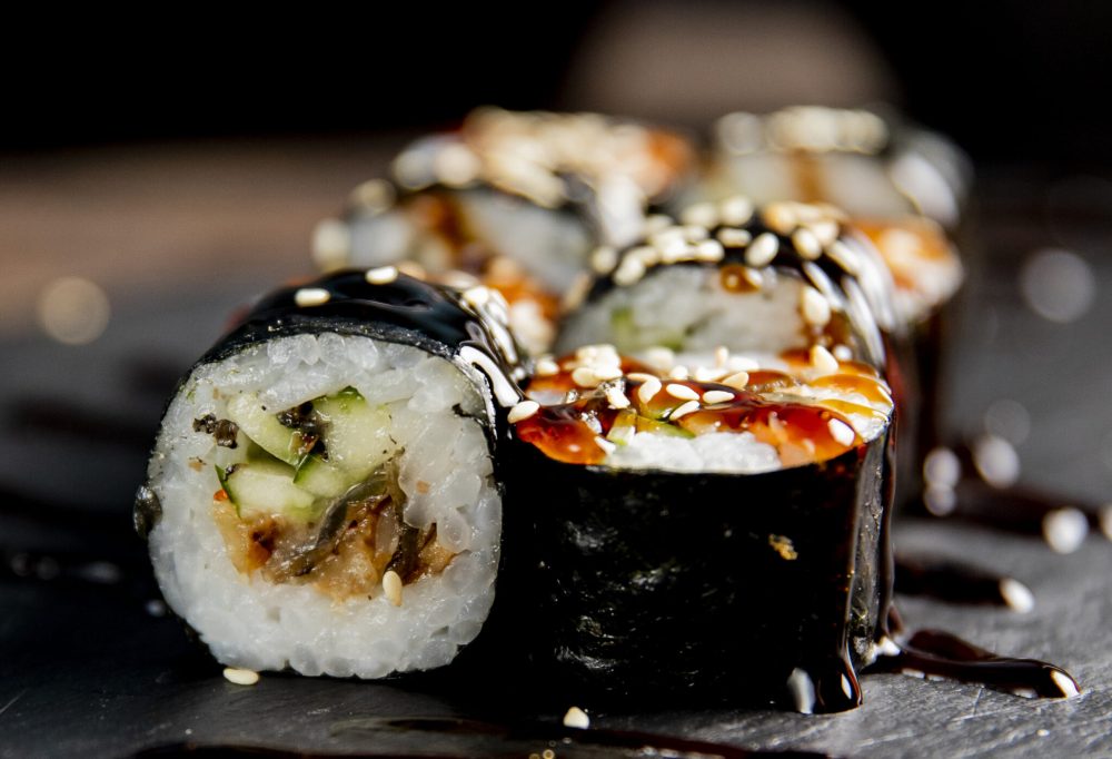 maki roll with cucumber served with sauce and sesame seeds